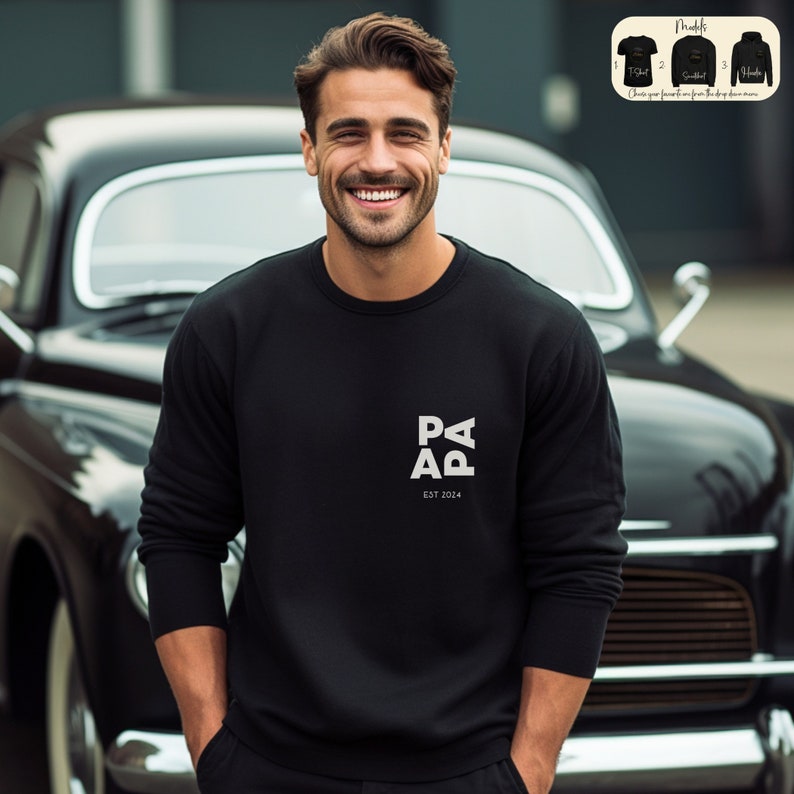 Op de afbeelding: Zwart sweatshirt met een witte afbeelding met de tekst "PAP" en "EST 2024".