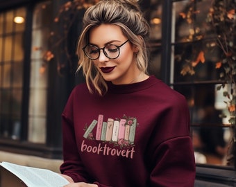 May include: A maroon sweatshirt with a graphic of stacked books with flowers and the text "booktrovert".