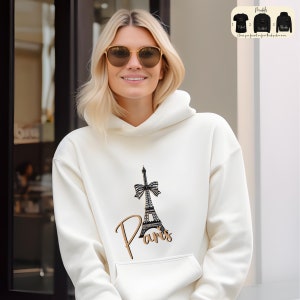a woman wearing a white hoodie with a picture of the eiffel tower