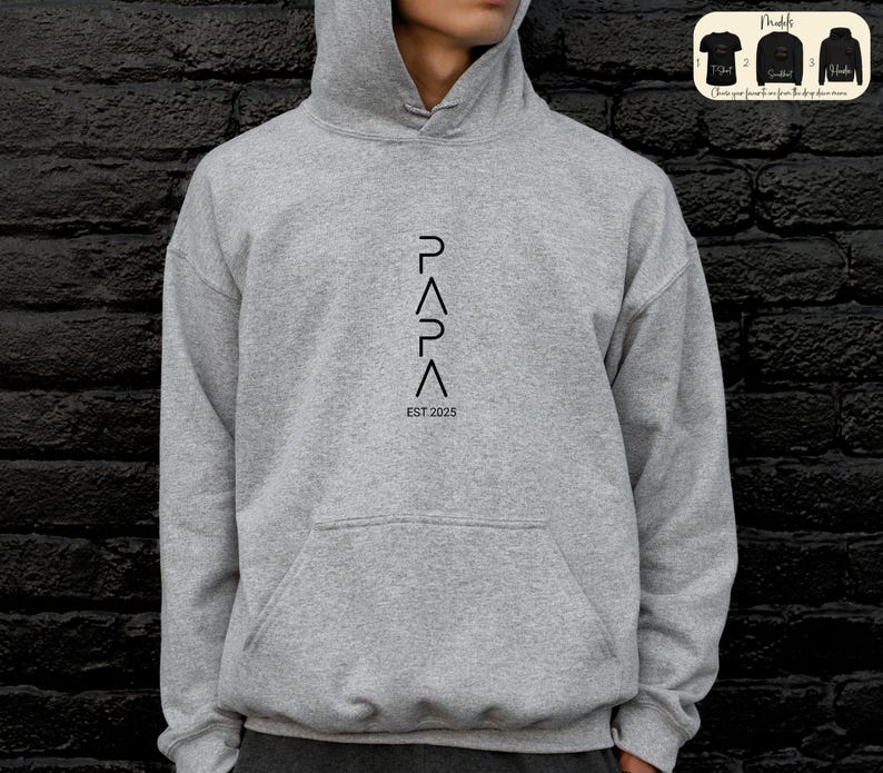 May include: A gray hooded sweatshirt with a black graphic design that reads "PAPA" with a triangle symbol between each letter and "EST 2025" below the graphic.