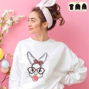May include: White sweatshirt with a graphic of a bunny wearing pink glasses and a pink bandana. The bunny is blowing a pink bubble.