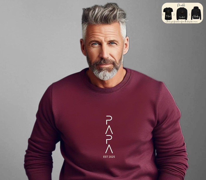 May include: A maroon sweatshirt with a white graphic design that reads "PAPA" with a triangle shape for each letter. The text "EST 2025" is below the graphic.