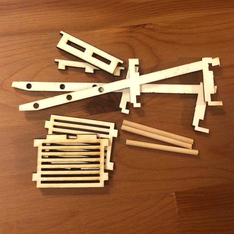 K&ouml;nnte beinhalten: Ein Satz aus Holzbausteinen zum Bau eines Modells. Das Set enth&auml;lt verschiedene Formen und Gr&ouml;&szlig;en von Holzst&uuml;cken, darunter zwei lange St&uuml;cke, zwei kurze St&uuml;cke und ein quadratisches St&uuml;ck mit einem Gittermuster. Die St&uuml;cke sind alle aus hellem Holz gefertigt.