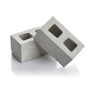 May include: Two grey concrete breeze blocks with two rectangular holes in each block.