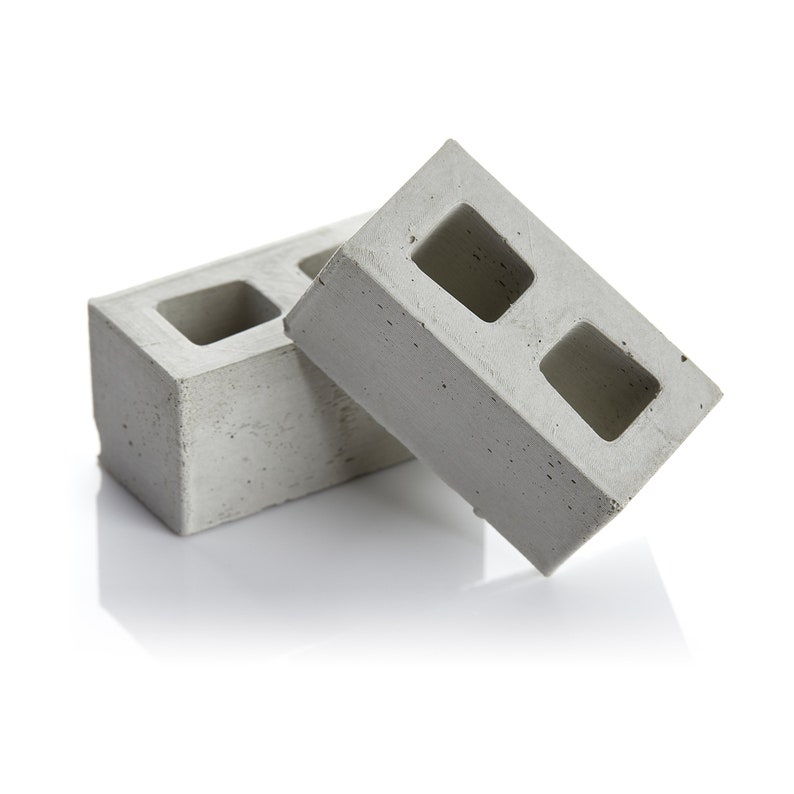 May include: Two grey concrete breeze blocks with two rectangular holes in each block.
