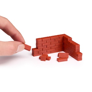 Peut inclure: Un mur en briques rouges est en construction avec des briques individuelles. Le mur est partiellement construit avec quelques briques encore détachées.