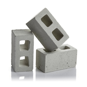May include: Three grey concrete cinder blocks stacked on top of each other. The top block is lying on its side.