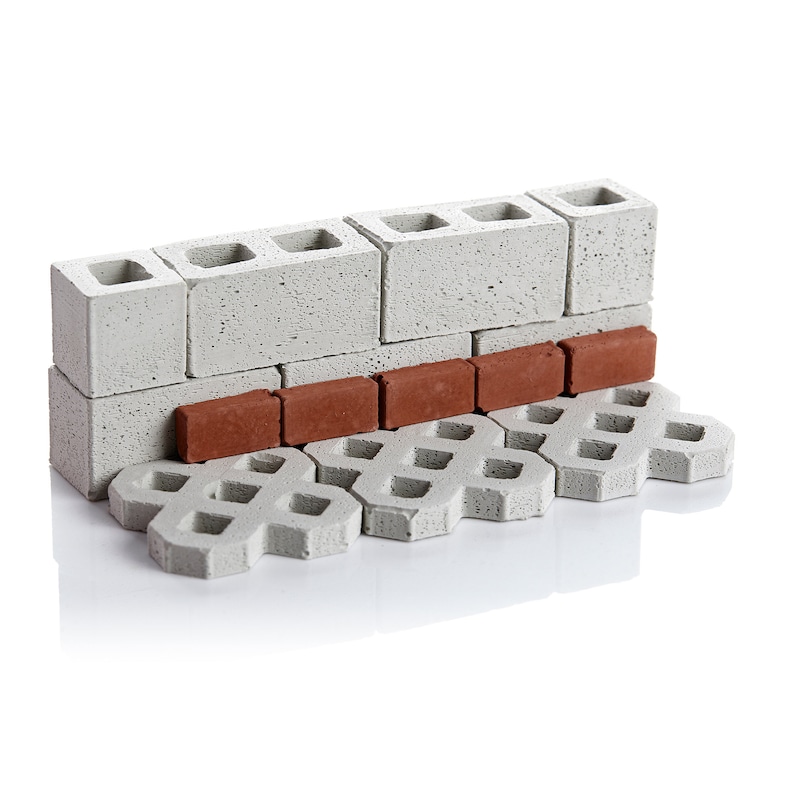 May include: A miniature model of a brick wall with a row of red bricks at the base and a grey concrete walkway below.