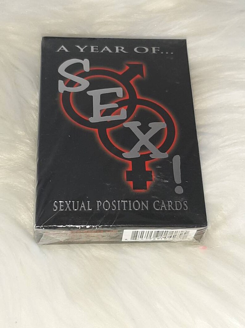 May include: A black deck of "Sexual Position Cards" is wrapped in clear plastic. The text "A YEAR OF... SEX!" is in silver, with the word "SEX" in large letters and red outlines. The words "SEXUAL POSITION CARDS" are in white.
