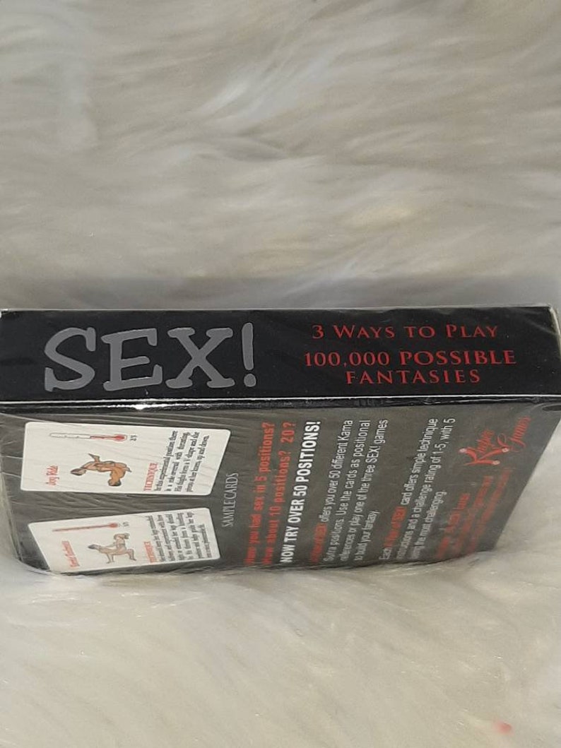 May include: A black box with the word "SEX!" in large white letters. The box also has the text "3 WAYS TO PLAY" and "100,000 POSSIBLE FANTASIES". Sample cards are visible, along with the text "NOW TRY OVER 50 POSITIONS!"