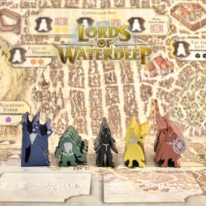 May include: The board game "Lords of Waterdeep" is displayed, featuring a detailed map-style game board and five wooden player pieces in various colours. The board includes city illustrations and text.