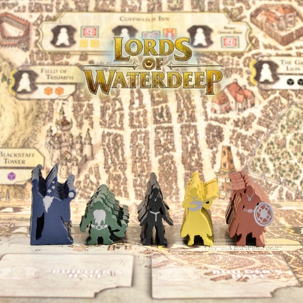 May include: A board game titled "Lords of Waterdeep" with a map-like game board and five wooden player pieces in blue, green, black, yellow, and brown. The game board features city illustrations and text.