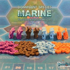 Puede incluir: Piezas de juego de Dominant Species: Marine. Las piezas de juego están hechas de madera y están pintadas en diferentes colores: morado, marrón, azul y naranja. Las piezas de juego están dispuestas en filas en un tablero de juego azul. El texto "Dominant Species: Marine" está impreso en la parte superior de la imagen.