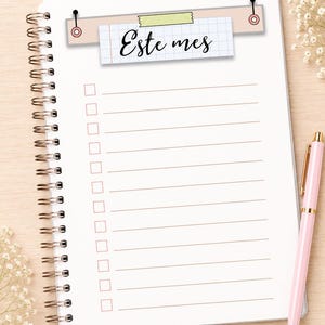 May include: A spiral-bound notebook with white pages featuring horizontal lines and a checklist column. At the top, a rectangular graphic displays the text "Este mes" on a grid-patterned paper strip, secured by a piece of light green tape.