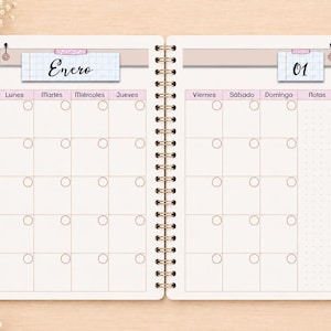 May include: A spiral-bound planner open to a monthly calendar spread. The left page is labeled Enero and the right page is labeled 01. The grid features columns for days of the week in Spanish, small circular icons in each box, and a notes section.