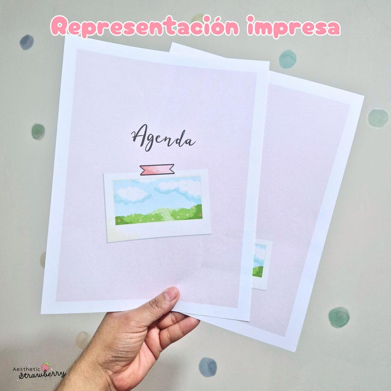 May include: Two printed sheets of paper with a light lavender background. The top sheet features the word Agenda in black script, a pink rectangular graphic, and a small illustration of a blue sky with white clouds over a green landscape.