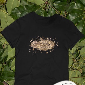 Puede incluir: Camiseta negra con un gráfico de una serpiente marrón y blanca enroscada en un círculo con un efecto acuarela.