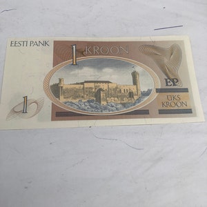 May include: A one Estonian kroon banknote featuring a brown and white image of a castle with a tower. The text "Eesti Pank" and "1 Kroon" are printed on the banknote.