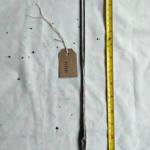 May include: A metal tool with a pointed end, approximately 15 inches long, next to a measuring tape. A small tag with the number "002146" is attached to the tool. The tool appears to be vintage.