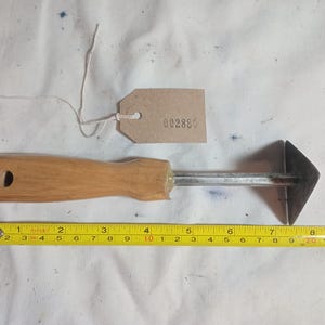 May include: A vintage metal and wood tool with a triangular head, a wooden handle, and a metal shaft. A yellow measuring tape shows the tool is approximately 20 cm long. A small tag with the number "002880" is attached.