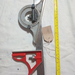 May include: A combination square and a measuring tape are shown. The combination square is metal with a red head. The measuring tape is yellow and black, showing measurements. The square's blade is approximately 30 cm long.