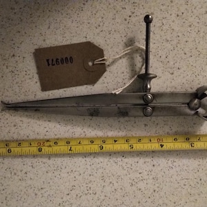 May include: A silver metal caliper with a brown paper tag labelled "126000". The caliper is used for measuring the inside diameter of objects.