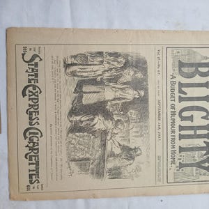 May include: Aged newspaper cover titled "BLIGHTY" with the subtitle "A BUDGET OF HUMOUR FROM HOME." The illustration depicts people in a scene. The text "STATE EXPRESS CIGARETTES" is also present. A small tag with the number "002165" is attached.