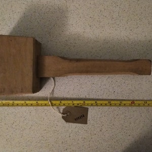 May include: A wooden mallet with a long handle, measuring 15 inches in length. The mallet is brown and has a slightly rounded head. A brown tag with the text "001424" is attached to the handle.