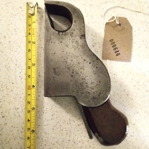 May include: A vintage metal hand plane with a wooden handle. The plane is approximately 8 inches long and has a metal tag with the number 000646 on it.