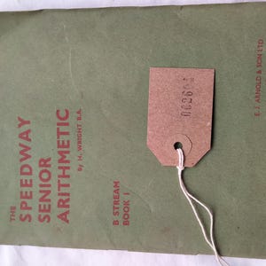 May include: A vintage green arithmetic textbook titled "The Speedway Senior Arithmetic" with a brown price tag attached. The book's cover features red text and the publisher's name.