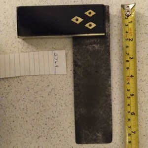 May include: A black and brass try square with a black handle and three brass diamond-shaped inlays. The try square is 20 cm long and is measured with a yellow tape measure.