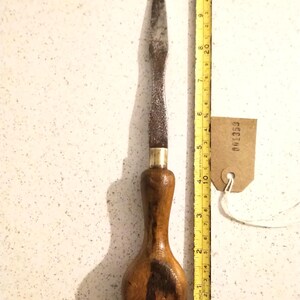 Peut inclure: Un tournevis plat ancien avec un manche en bois et une lame en métal. Le tournevis mesure environ 25 cm de long, avec une virole en laiton. Une étiquette avec le numéro "001359" est attachée.