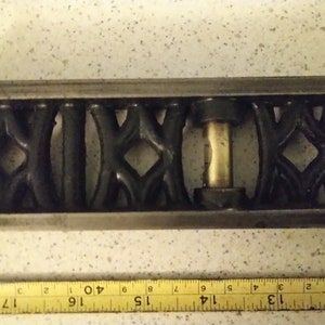 May include: A black metal spirit level with a brass bubble level. The level has a decorative design with a repeating pattern.