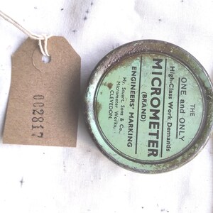 May include: A vintage micrometer in a green tin, labelled "MICROMETER (BRAND)" and "ENGINEERS' MARKING." A brown tag with "002817" is attached. A yellow tape measure shows measurements in feet and inches.