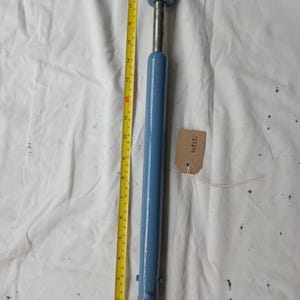 May include: A vintage blue and silver metal tool with a curved end and a cylindrical handle. The tool is approximately 51 cm long, with a metal shaft and a blue painted finish. A yellow measuring tape is next to the tool.