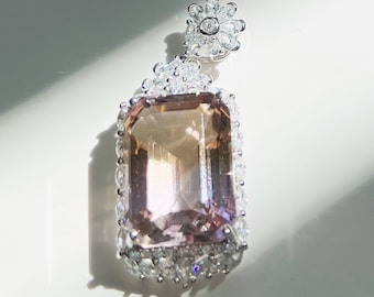 May include: A delicate pendant featuring a large, rectangular, light pink gemstone surrounded by a sparkling halo of smaller clear stones. The pendant is attached to a silver chain.
