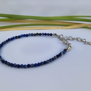 Op de afbeelding: Een blauwe lapis lazuli kralen armband met een zilveren sluiting en een verlengketting.