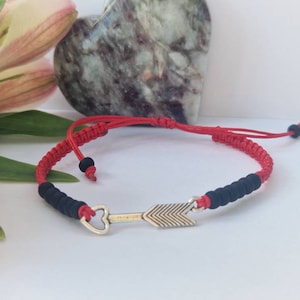 May include: Red and black braided bracelet with a silver arrow and heart charm.