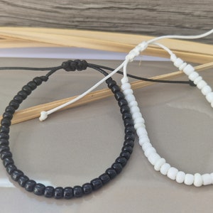 Puede incluir: Dos pulseras ajustables con cuentas negras y blancas. La pulsera negra tiene un cord&oacute;n negro y la pulsera blanca tiene un cord&oacute;n blanco.