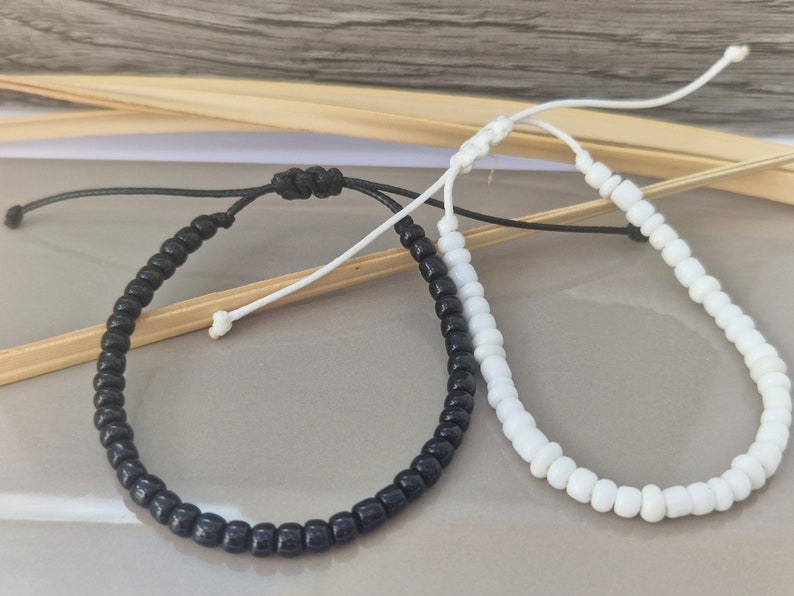 Puede incluir: Dos pulseras ajustables con cuentas negras y blancas. La pulsera negra tiene un cord&oacute;n negro y la pulsera blanca tiene un cord&oacute;n blanco.