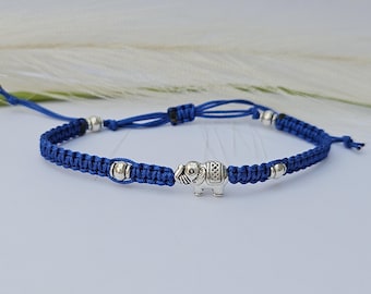 May include: A blue braided bracelet with silver beads and a silver elephant charm.