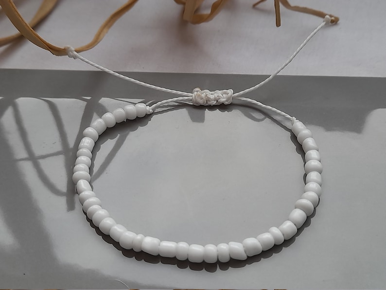 Puede incluir: Pulsera de cuentas blancas con cierre de cord&oacute;n blanco.