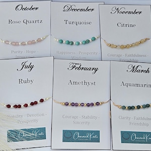 May include: A collection of gemstone bracelets displayed on cards. Each card features a month, gemstone name, and associated virtues. Bracelets include Rose Quartz, Turquoise, Citrine, Ruby, Amethyst, and Aquamarine. The "Charmed Knots" logo is visible.