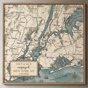 May include: A square framed map of New York City and surrounding areas in beige and blue tones. A decorative rectangular box in the lower left corner contains the text: LUCY & JACK engaged NEW YORK, NY 11.25.2026, featuring a compass rose.