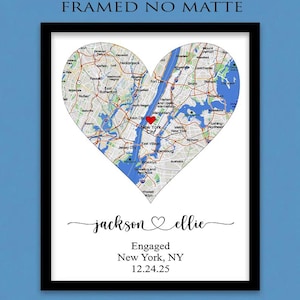 May include: A framed print featuring a heart-shaped map of New York City with a red heart icon over Manhattan. Below the map, the text reads jackson and ellie with a heart symbol, followed by Engaged, New York, NY, and the date 12.24.25.
