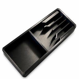 Könnte beinhalten: Ein schwarzer, rechteckiger Organizer mit mehreren Fächern. Er hat einen großen offenen Bereich und einen Bereich mit abgewinkelten Trennwänden. Der Organizer besteht aus mattem, schwarzem Material.