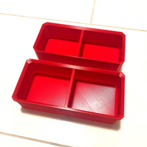 Puede incluir: Dos cajas de almacenamiento de plástico rojo con divisores. Cada caja tiene dos compartimentos.