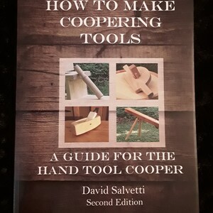 K&ouml;nnte beinhalten: Ein Buch mit dem Titel "How to Make Coopering Tools: A Guide for the Hand Tool Cooper" von David Salvetti, zweite Auflage. Der Umschlag zeigt einen Holzmaserungshintergrund mit vier Bildern von B&ouml;ttcherwerkzeugen.