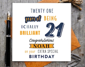 May include: A square greeting card with dark blue and orange text that reads: TWENTY ONE years of BEING TOTALLY BRILLIANT 21 Congratulations NOAH on your EXTRA SPECIAL BIRTHDAY. The card is white with a black fountain pen and paper clips.