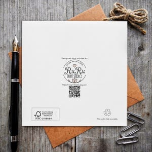 K&ouml;nnte beinhalten: Eine quadratische wei&szlig;e Gru&szlig;karte mit einem zentralen kreisf&ouml;rmigen Logo mit dem Text RuRu PRINT STUDIO, einem QR-Code und dem Text Designed and printed by MADE WITH LOVE. Die Karte enth&auml;lt ein FSC-Logo, ein Recyclingsymbol und den Text This card is fully recyclable.